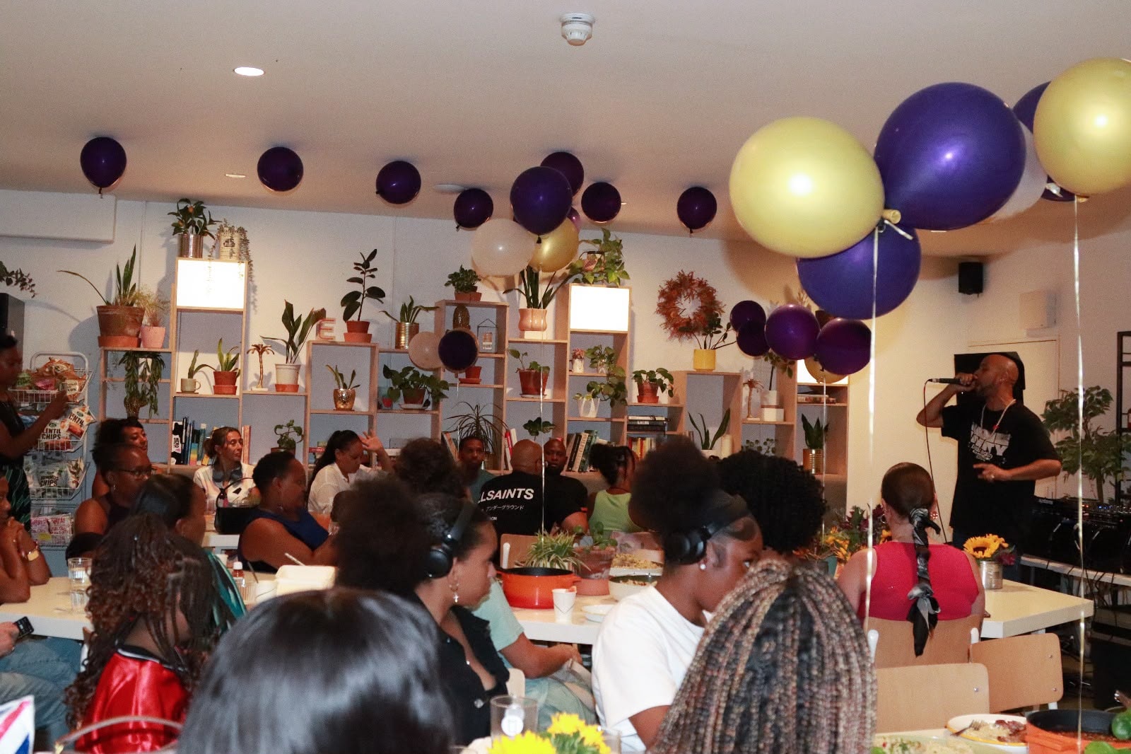 MC performing on stage at the EKing Foundation event — purple and gold balloons fill the ceiling