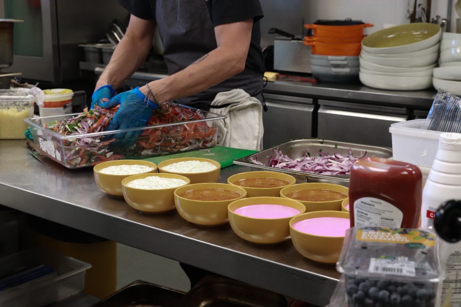 Kitchen prep — colourful bowls of sauces and a chef tossing salad