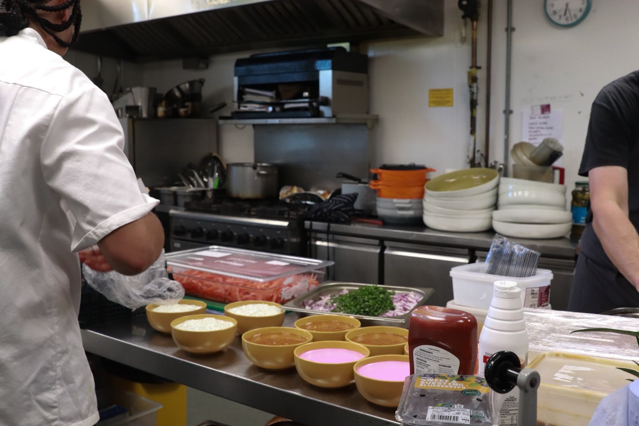 Kitchen team plating up — bowls of rice, sauce and fresh herbs ready to serve