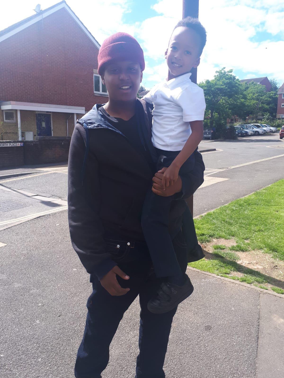 Eddie carrying a young child on a sunny street